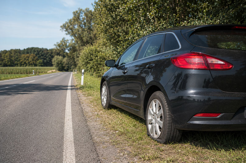 reifenpanne, fahrzeug mit plattem reifen am straßenrand